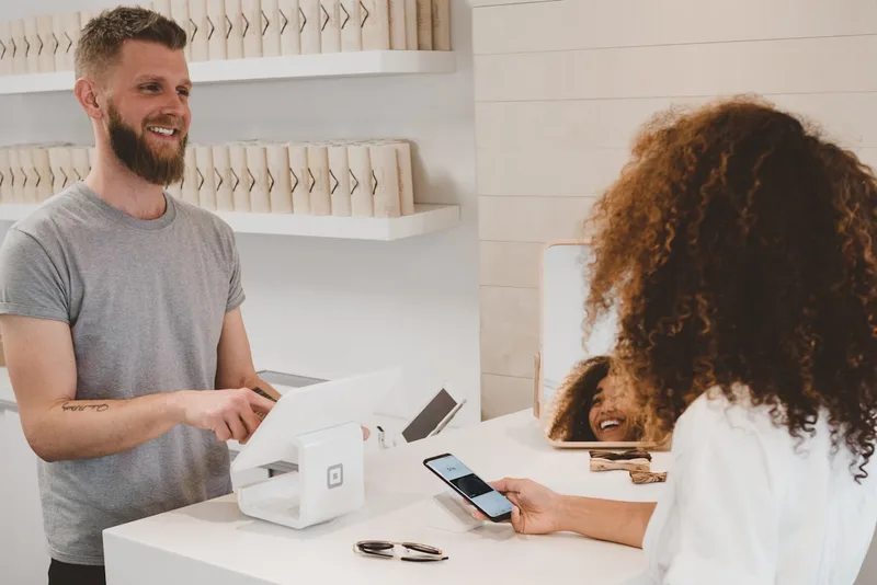 Person holding a credit card near a laptop, considering payment options for a discreet online purchase