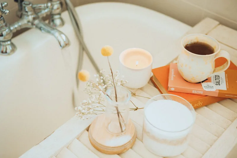 A cup of coffee and books resting on the edge of a bathtub, a quiet self-care moment