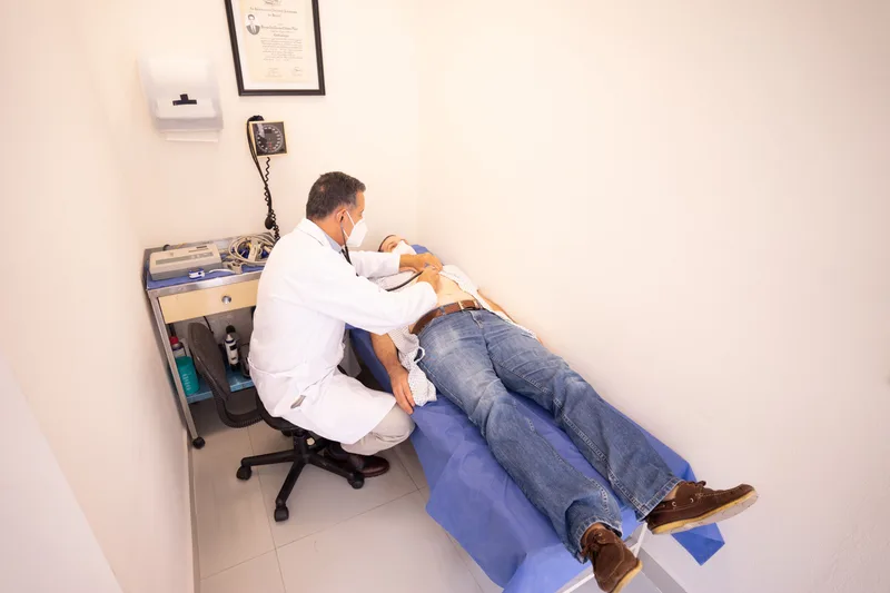 Doctor performing a stethoscope examination on a male patient lying on an exam table in a medical clinic