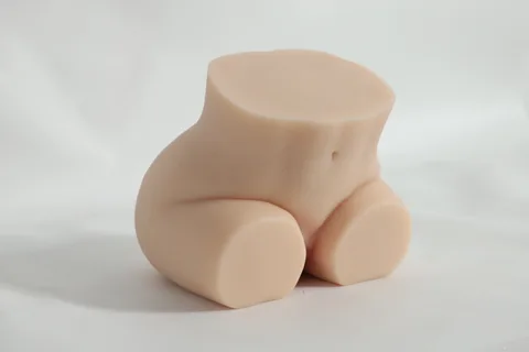 Angled view of the realistic silicone sex doll seated, showing belly button and abdomen