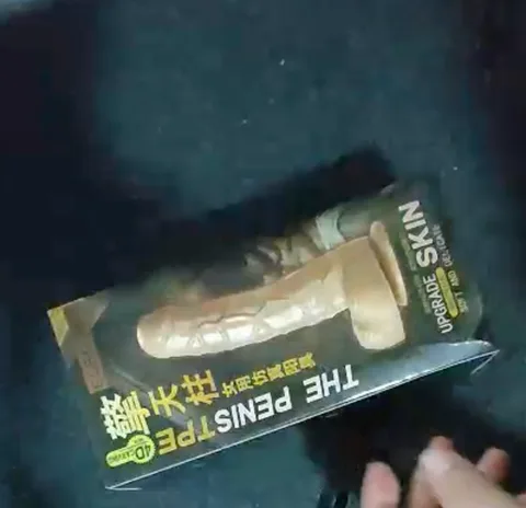 Wearable strap-on dildo set in its retail box with the skin-tone dildo and black harness visible